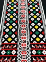 Близък план на тракийска престилка с геометрични шевици на черен фон и орнаменти тип „птици“.